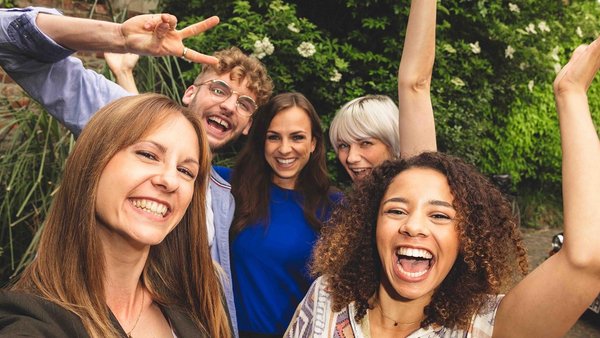 Σχεδιάζοντας διακοπές με φίλους – πώς λειτουργεί  Πέντε φίλοι στέκονται κοντά και γελούν στην κάμερα