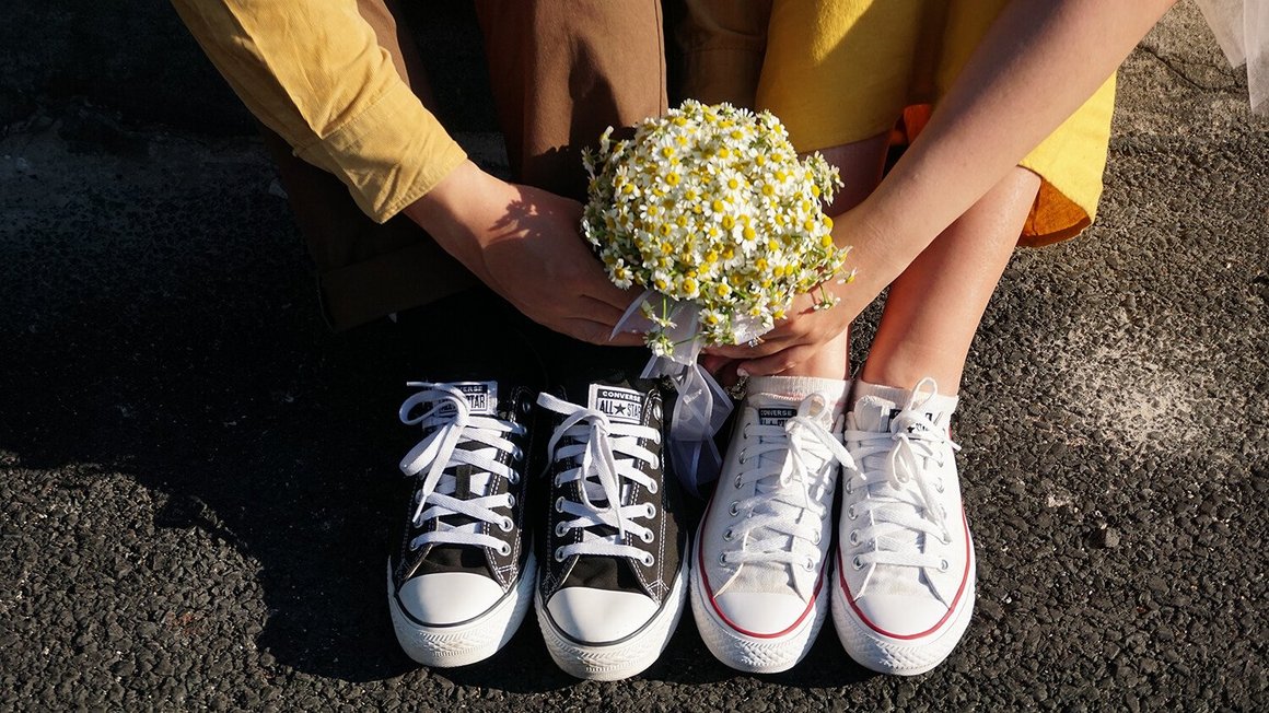 Ζευγάρι κάθεται στο έδαφος με λουλούδια στο χέρι – Οργάνωση Γάμου 