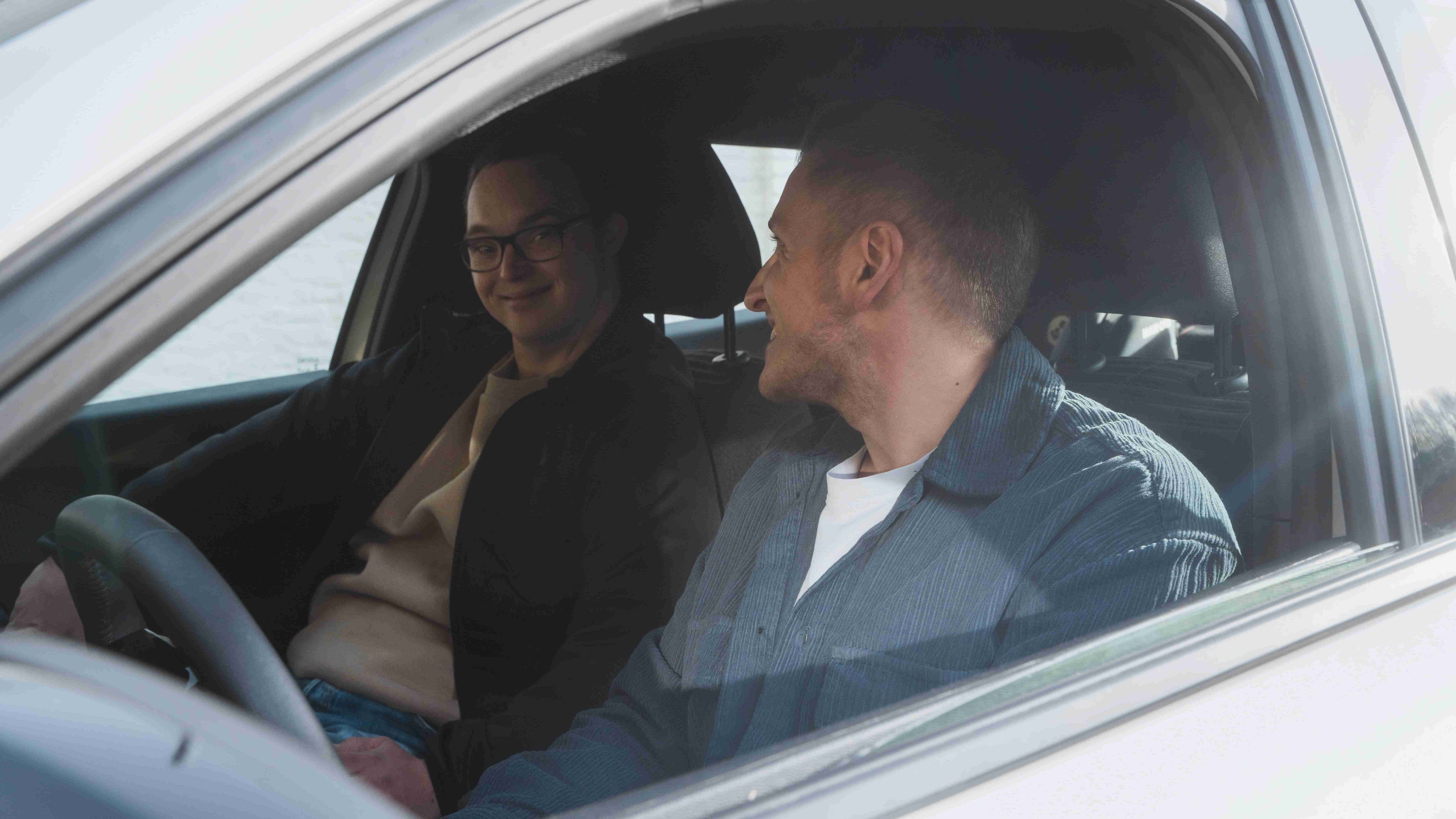 Δύο νεαροί άντρες κάθονται σε αυτοκίνητο και χαμογελούν 