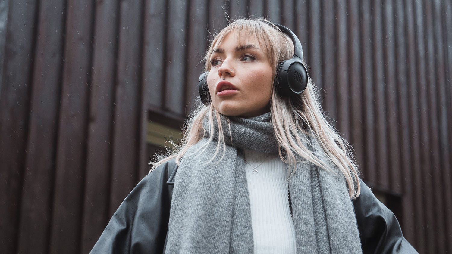 Νεαρή γυναίκα με ακουστικά κοιτάζει στο βάθος